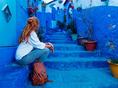 Frau sitzt auf einer Treppe in der blauen Stadt Chefchaouen in Marokko