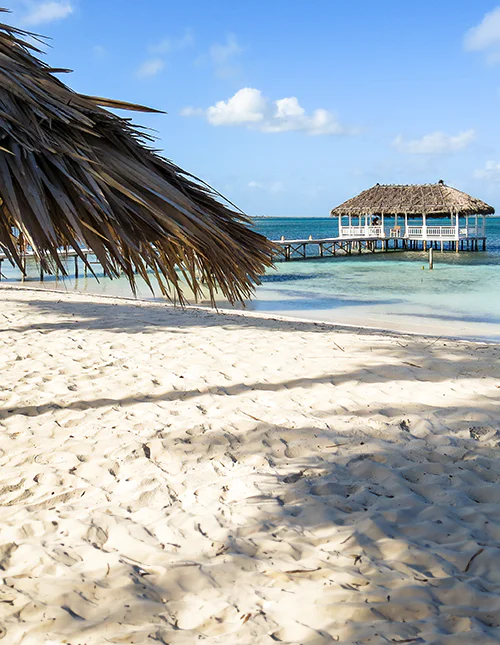 Weißer Sandstrand mit türkisfarbenem Meer und Bungalow auf Stelzen